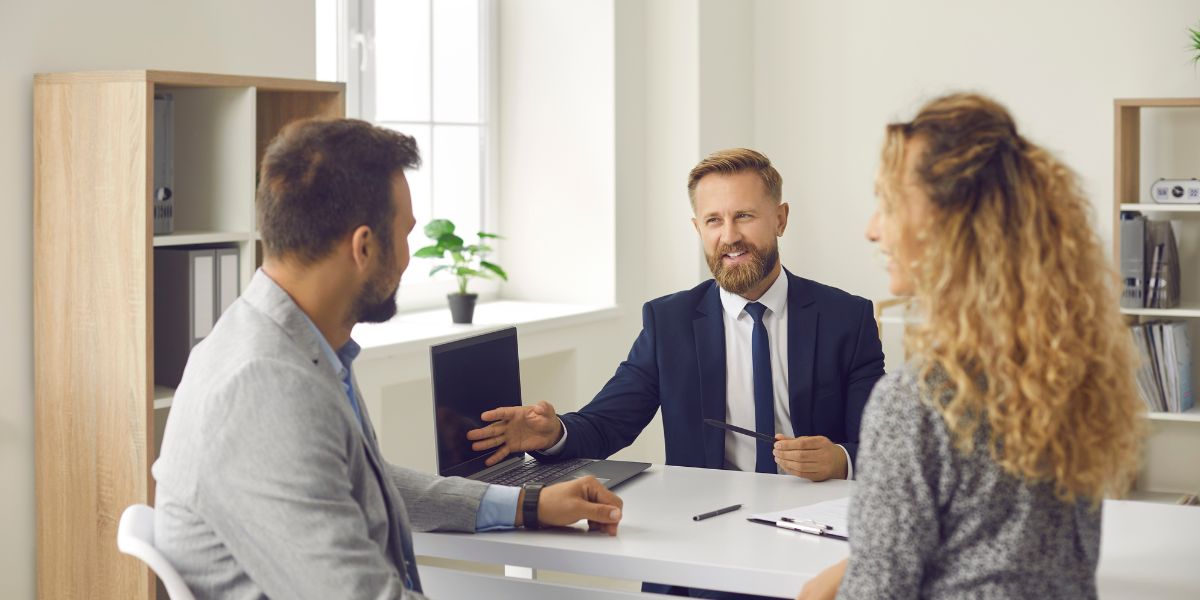 Insurance agent discussing options with a couple at a desk.