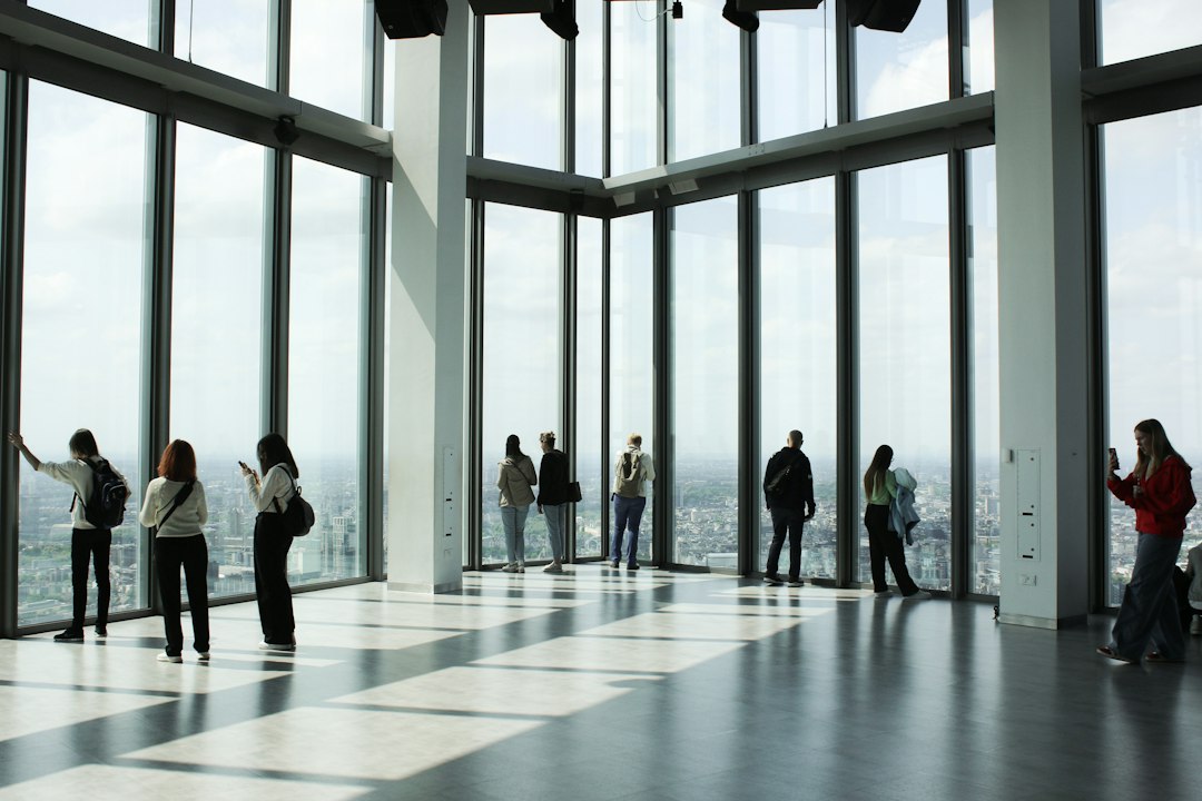 A real estate investor in a modern high-rise office looks out over a sprawling city, contemplating market risks and strategic decisions.